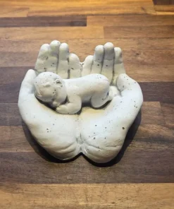 Hænder med baby i hvid cement